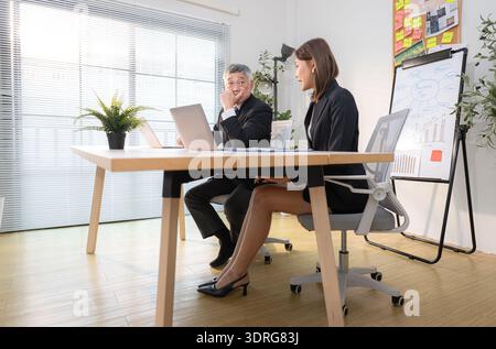 Patron et assistant sont sur une mission de surveiller l'avancement d'un projet d'entreprise Banque D'Images