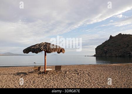 Un parasol avec un toit de chaume ombrage les touristes sur une plage à Nopolo, Baja, Mexique, près de la ville de Loreto. Banque D'Images
