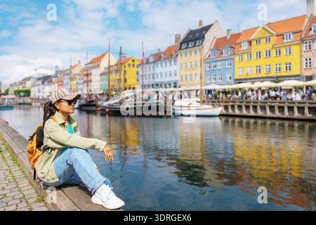 Charmant front de mer à Nyhavn, Copenhague, Danemark avec des bâtiments colorés et un touriste détendu Banque D'Images