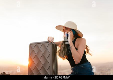 La voyageuse, qui a son sac de voyage à côté d'elle, parle au téléphone. Banque D'Images