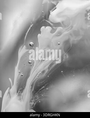 Fond abstrait monochrome avec liquide blanc coulant et bulles d'air. Texture crémeuse en mouvement, macro artistique minimale. Idéal pour cosmétique Banque D'Images
