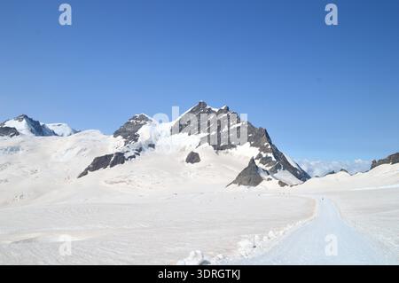 Le pic de la Jungfrau s'élève au-dessus d'un glacier couvert de neige avec l'observatoire du Sphinx sur le Jungfraujoch dans les Alpes bernoises, en Suisse Banque D'Images