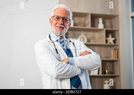 Médecin masculin senior mature dans des lunettes uniforme médical souriant regardant la caméra dans l'hôpital ou le cabinet du médecin. Médecine générale Banque D'Images