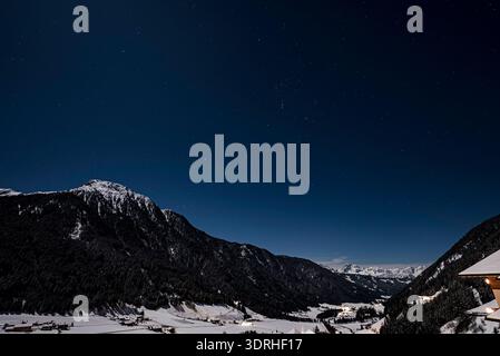 Le moment où la voie lactée et la lune se sont couchées sur un village des Alpes. Banque D'Images
