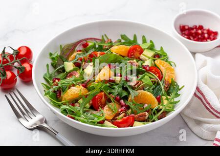 Salade de mandarine végétalienne, avocat et tomates dans un bol, repas végétarien cru sain, vue de dessus, fond blanc Banque D'Images