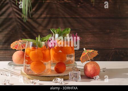 Thé de pêche glacé ou cocktail à la menthe et aux abricots, recette rafraîchissante de boisson estivale. Deux verres avec limonade de fruits de pêche sur un RU Banque D'Images