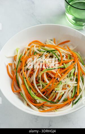 Concombre frais et sain, salade de carottes et de radis daikon dans un bol, nourriture crue végétalienne, vue de dessus Banque D'Images