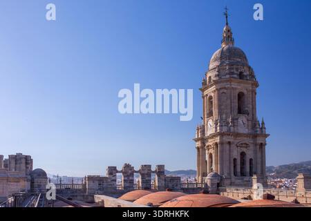 Large panorama sur le toit de la cathédrale de Malaga avec dômes en terre cuite et clocher. Espagne. Soleil brillant sur la ville méditerranéenne. Paysage architectural et hi Banque D'Images