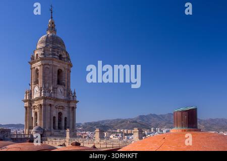 Large panorama sur le toit de la cathédrale de Malaga avec dômes en terre cuite et clocher. Espagne. Soleil brillant sur la ville méditerranéenne. Paysage architectural et hi Banque D'Images