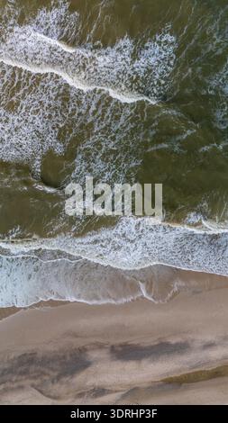 Les vagues s'écrasent sur les rives sablonneuses d'une plage paisible au Danemark pendant le coucher du soleil Banque D'Images