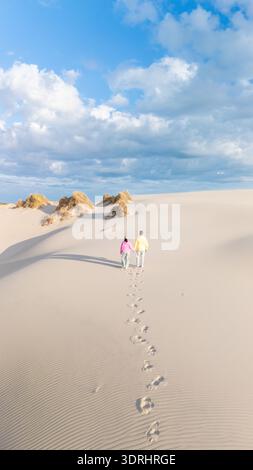 Couple marche main dans la main à travers les superbes dunes de sable du Danemark sous un ciel bleu Banque D'Images