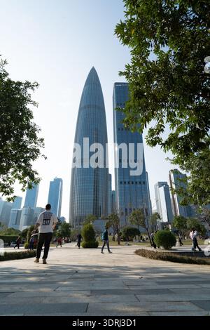 Gratte-ciel modernes dans l'horizon de la ville de Shenzhen avec des piétons marchant sous les arbres le jour ensoleillé Banque D'Images