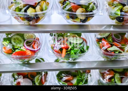 Boîtes en plastique avec salades de fruits et légumes préemballées, mises en vente dans un réfrigérateur commercial Banque D'Images