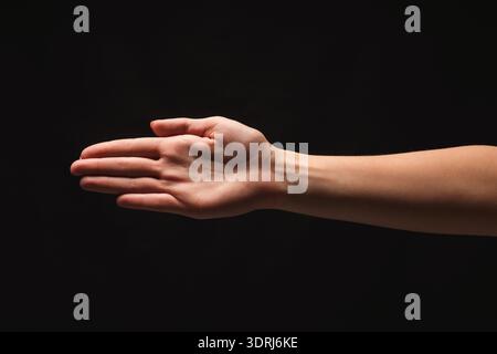 Main tendue dans un espace sombre, mettant en valeur l'ouverture et la connexion dans un collage de gestes Banque D'Images