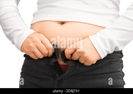 Gros plan d'une personne luttant pour boutonner un Jean noir serré sur son ventre, isolé sur un fond blanc. Concept de prise de poids, obésité, et mourir Banque D'Images