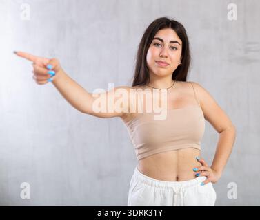 Jeune femme souriante faisant des gestes en studio Banque D'Images