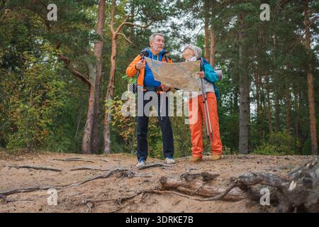 Tourisme de randonnée. Senior couple homme femme regardant la piste dans la carte de papier appréciant la randonnée dans la forêt. Heureux vieux randonneurs routards Banque D'Images