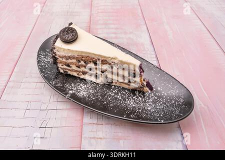 Cette photographie révèle la tranche parfaite d'un gâteau au chocolat, mettant en valeur tout, du biscuit croquant et de la base de noix aux couches successives de Banque D'Images