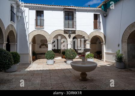 Cour ensoleillée avec pavage en pierre, arches, balcons et fontaine centrale au Santuario de NTRA. SRA. De la Sierra près de Cabra, Córdoba, Espagne. Banque D'Images