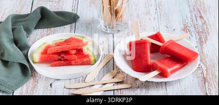 Pastèque popsicles sur des bâtons en bois sur une assiette sur une bannière de toile de table Banque D'Images