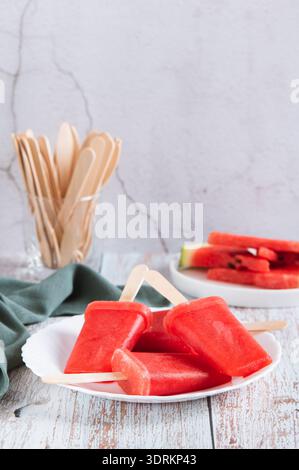 Pastèque popsicles sur bâtons de bois sur une assiette sur une vue verticale de table Banque D'Images