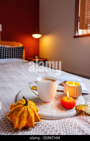 Scène d'automne confortable avec une tasse de café chaude, des citrouilles décoratives et une bougie sur un plateau en marbre, créant une atmosphère relaxante Banque D'Images