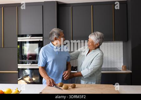 Couple senior préparant le repas ensemble dans la cuisine moderne, partageant le moment joyeux. Cuisine, culinaire, compagnie, bonheur, lov Banque D'Images