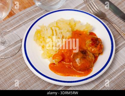assiette ronde blanche avec boulettes de viande saupoudrées d'aneth haché dans une sauce tomate avec purée de pommes de terre Banque D'Images