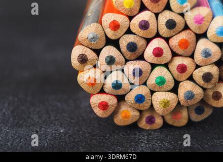 Collection colorée de crayons disposés dans un ensemble sur une surface noire pour des activités créatives Banque D'Images