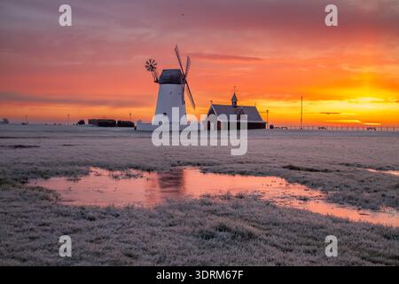 Lever de soleil givré au moulin à vent de Lytham, Lytham St Annes, avec le ciel brillant reflété dans les flaques d'hiver. Banque D'Images
