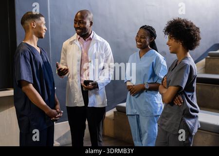 Docteur titulaire d'un prix, souriant avec des professionnels de la santé dans les gommages discutant à l'hôpital. Santé, travail d'équipe, réussite, re Banque D'Images