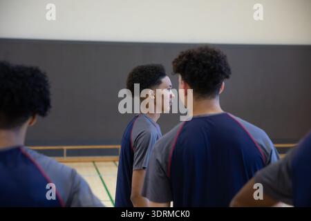 Joueurs masculins afro-américains adolescents debout sur le terrain de gymnastique de l'école avec des lignes dans les hauts de pratique Banque D'Images