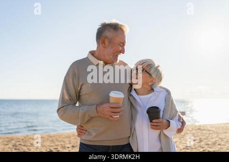 Bonjour. Couple mature senior appréciant la marche avec des tasses en papier de café. Vieille femme de mari buvant du café pour aller à l'extérieur. G Banque D'Images