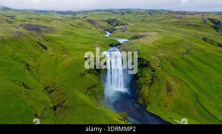 Découvrez la beauté époustouflante de la cascade de Skogafoss en Islande, où l'eau coule de façon spectaculaire sur les falaises escarpées, surr Banque D'Images