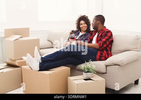 Couple se détend sur canapé parmi les boîtes de déménagement dans New Home Banque D'Images
