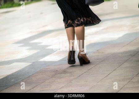 femme marchant dans la rue portant une paire de bottines à lacets en cuir marron avec un talon épais. Alghero, Italie Banque D'Images