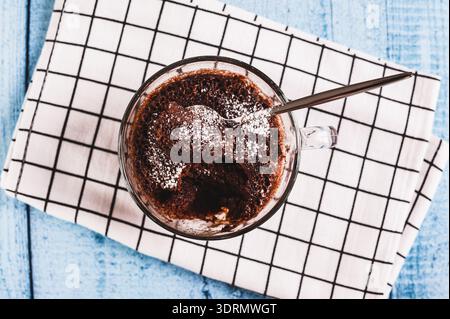 Gros plan de cupcake au chocolat avec du sucre en poudre dans une tasse sur la vue de dessus de table Banque D'Images