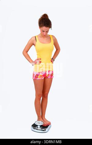 Junge Frau auf der WaageJunge Frau auf der Personenwaage Banque D'Images