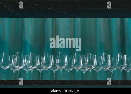 Élégante rangée de verres à vin en cristal disposés sur une surface sombre avec toile de fond Banque D'Images