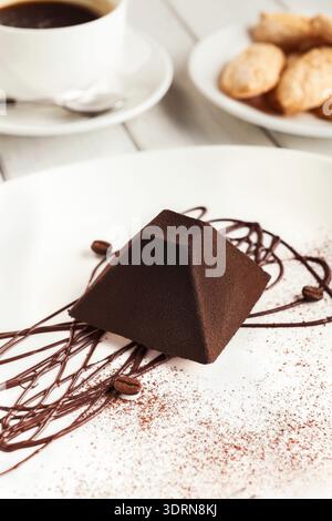 Dessert au chocolat servi avec du café et des cookies sur une assiette lors d'un rassemblement confortable dans un café Banque D'Images