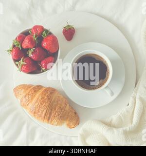 Petit déjeuner au lit. croissant, tasse de café et fraise fraîche Banque D'Images