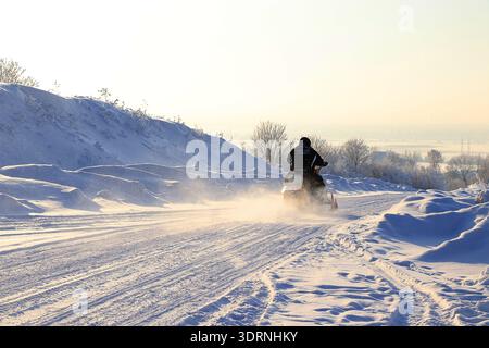 Sports d'hiver en plein air en Russie.sur la photo, les athlètes en motoneige roulent sur la route enneigée, dans une zone sauvage impraticable.Surround Banque D'Images