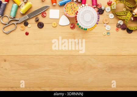 Collage créatif d'outils de couture et de matériaux sur une table en bois avec différentes couleurs et formes Banque D'Images