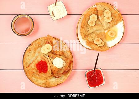 Délicieuses crêpes russes avec du fromage à pâte molle, des bananes et du caviar rouge sur la table de la cuisine. Petit déjeuner sain avec des ingrédients frais Banque D'Images
