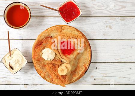Délicieuses crêpes russes avec du fromage à pâte molle, des bananes et du miel sur la table de la cuisine. Un petit déjeuner sain à base de fraîchement ingéré Banque D'Images