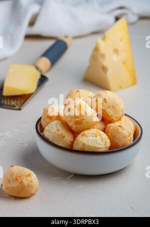 Pain au fromage brésilien. Petits pains au fromage faits maison fraîchement cuits dans une assiette blanche sur fond clair. Une collation gourmande. Délicieux PA Banque D'Images