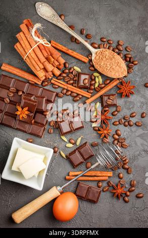 Ingrédients pour les desserts - chocolat noir, cacao, café, cannelle, anis, cardamome. Condiments et épices sur fond noir. Banque D'Images
