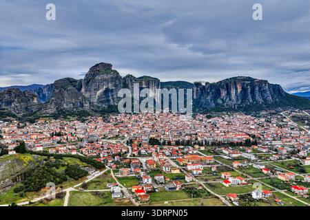 Kalambaka, Grèce. Photographie aérienne montrant les toits de tuiles rouges de la ville sous les imposants piliers rocheux des Météores, capturant le contraste entre u Banque D'Images