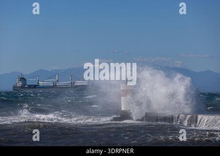 Une collection de photographies côtières spectaculaires montrant un cargo naviguant sur une mer agitée, de puissantes vagues s'écrasant contre une jetée en béton et un méta Banque D'Images