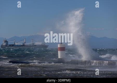Une collection de photographies côtières spectaculaires montrant un cargo naviguant sur une mer agitée, de puissantes vagues s'écrasant contre une jetée en béton et un méta Banque D'Images